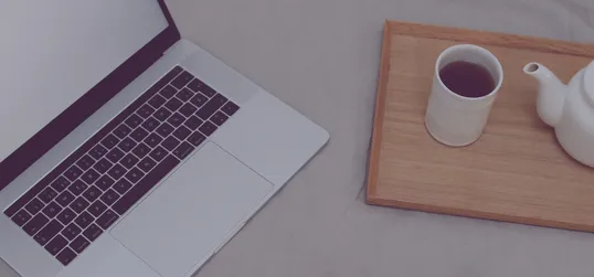 This is a image of a laptop, a cup of coffee, and a jar in a table.