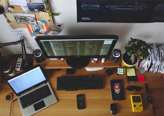 This image shows a table with a laptop, screen monitor, and other devices.